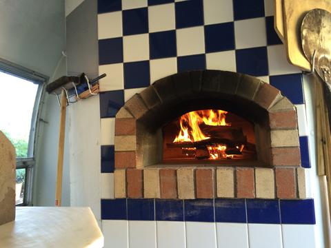 Photo interior of Airstream kitchen looking into oven with fire.