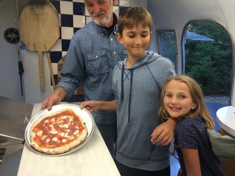 Photo of Darrold, Anthony and Celia in Airstream kitchen with Anthony&#039;s pizza