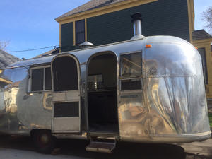 Photo of Airstream trailer with open door in driveway.